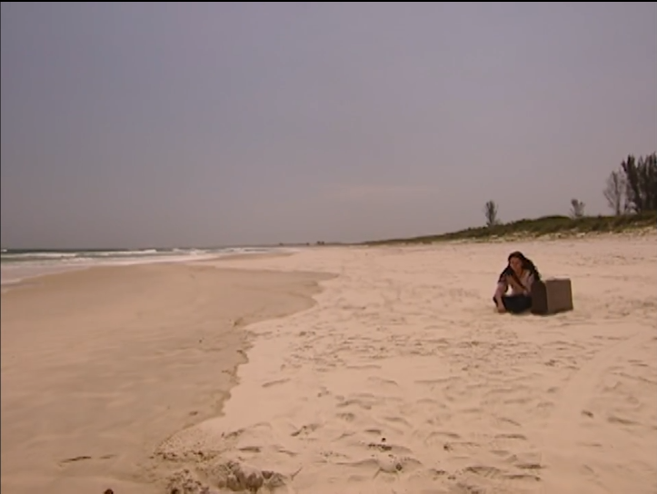 Jade with suitcase on a deserted beach