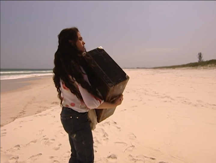 Jade with suitcase on a deserted beach