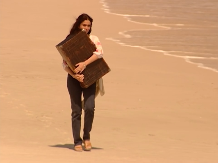 Jade with suitcase on a deserted beach