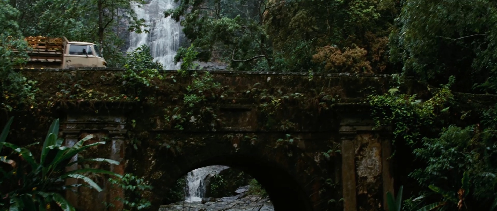 A truck passes the bridge with Cascatinha Taunay behind it