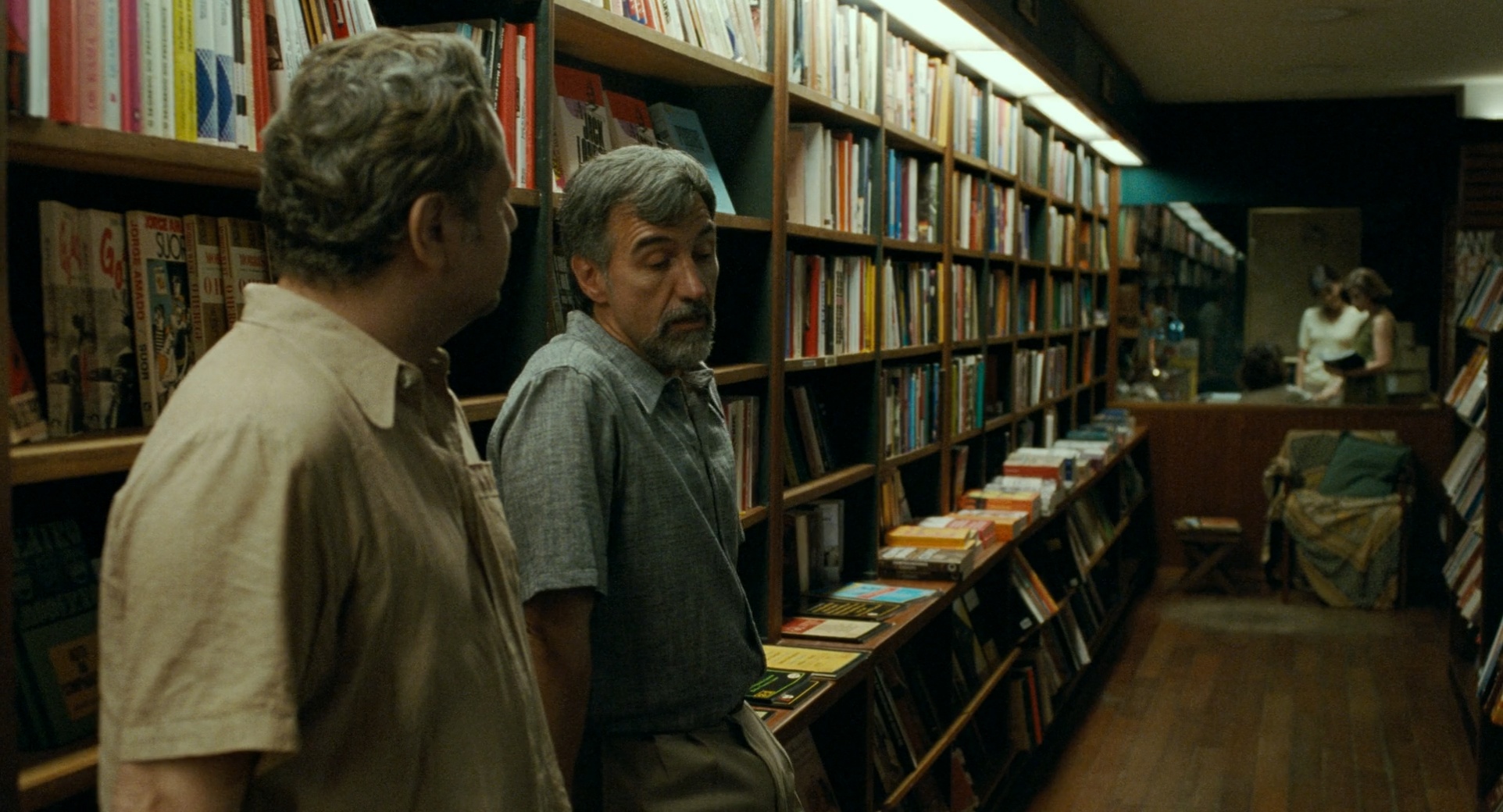 Characters talk among the bookshelves inside Livraria Argumento